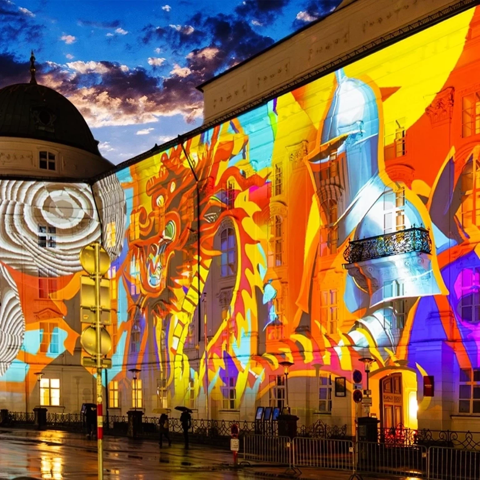 The facade of the Hofburg Innsbruck is decorated with colorful illumination featuring a knight and a dragon