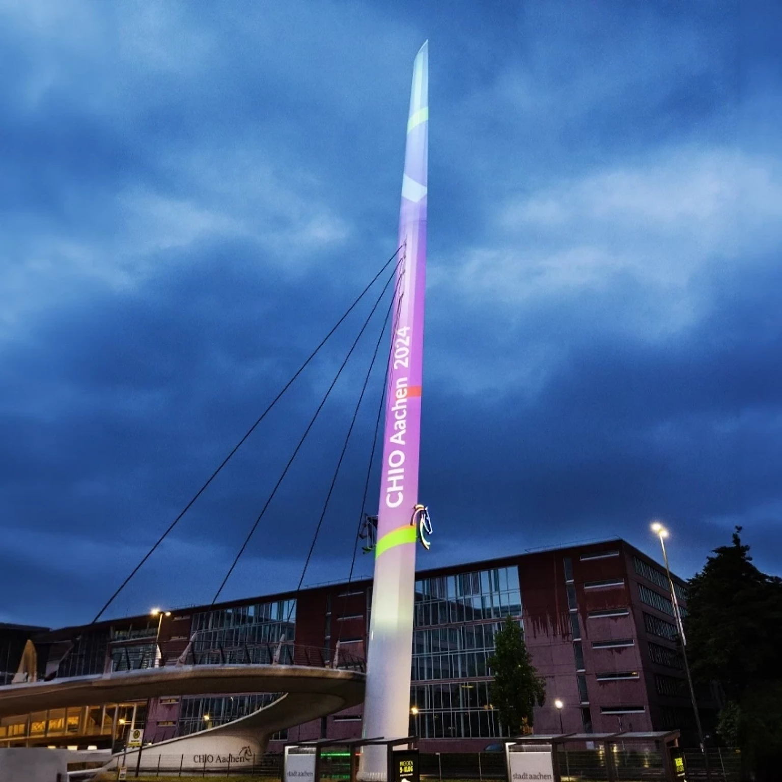 Die Aufschrift "CHIO Aachen 2024" auf einem rosafarbenen Hintergrund ist als großflächige Projektion auf der CHIO Nadel zu sehen