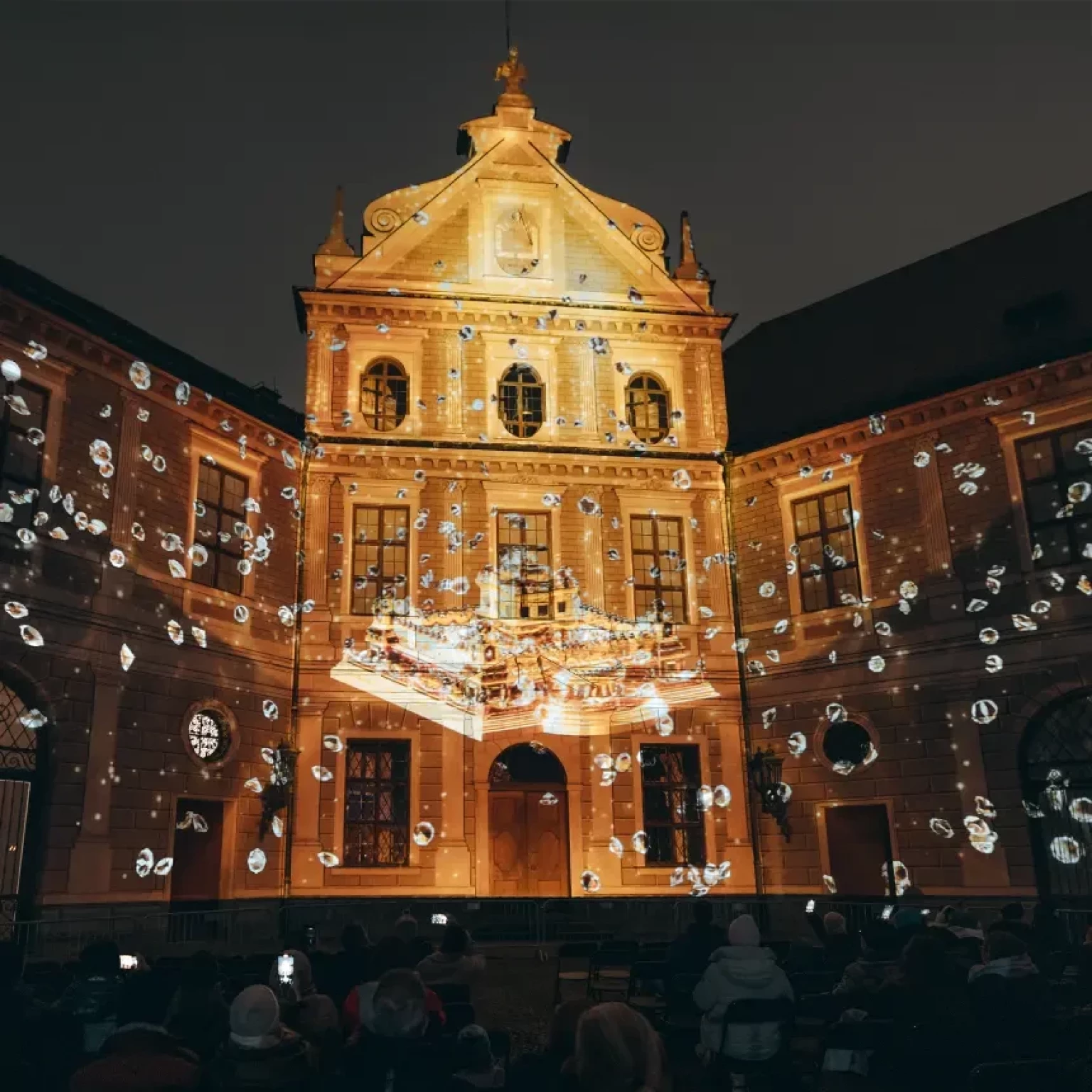 A building-specific projection onto the main portal of the fountain courtyard shows a jewelry box and free-flying diamonds.